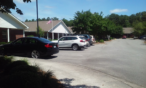 A view of a parking lot with several vehicles and a building in the background on a sunny day.