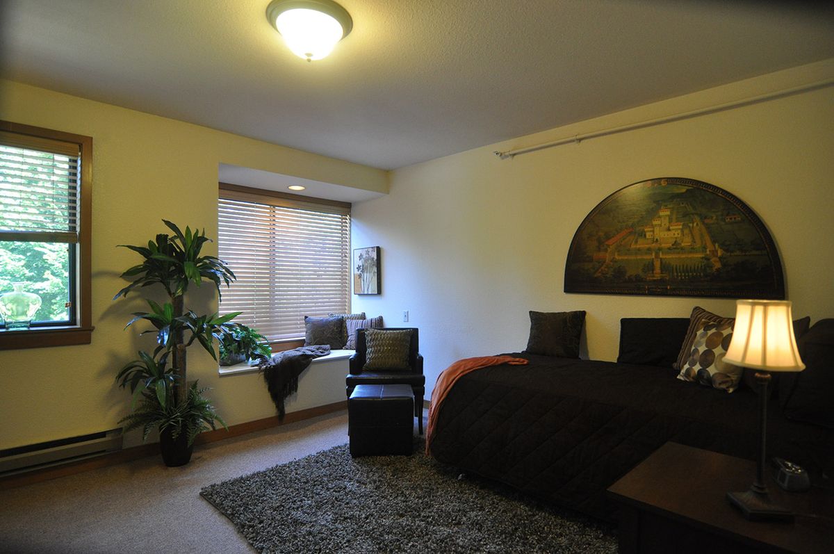 A cozy bedroom with modern decor, featuring a large bed, a window seat, and ambient lighting.