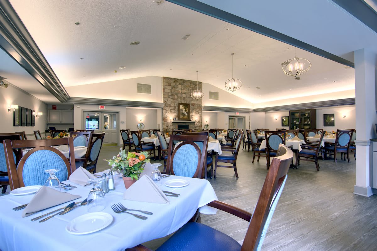An elegant dining room with neatly arranged tables and chairs, featuring sophisticated place settings and ambient lighting.