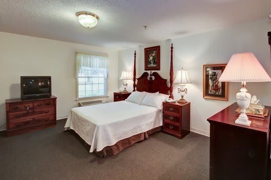 A traditional-style bedroom featuring a large bed, wooden furniture, and elegant lamps.