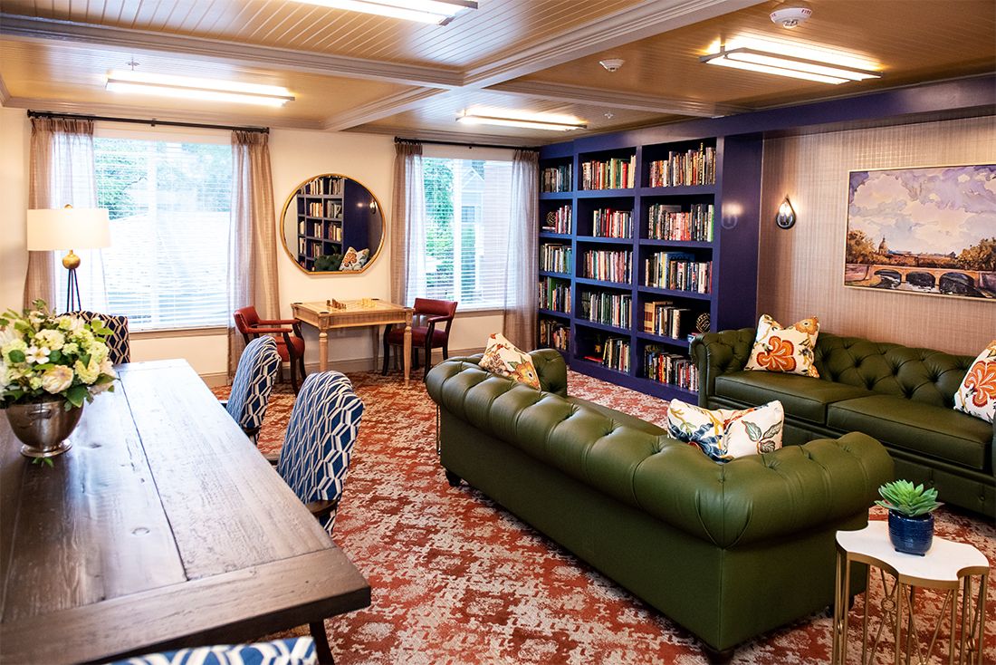 A cozy library room with a green sofa and extensive bookshelves.