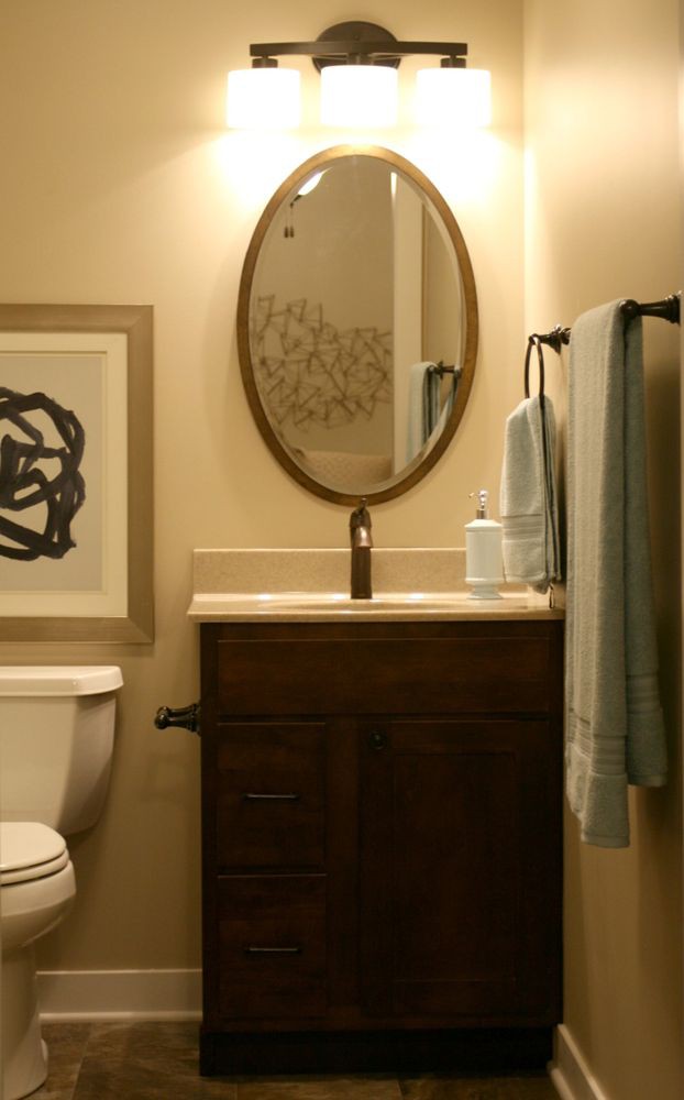 A cozy bathroom with a wooden vanity, oval mirror, and minimalist decor.