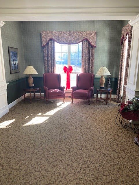 A cozy living room with two chairs by a window adorned with a large red bow.