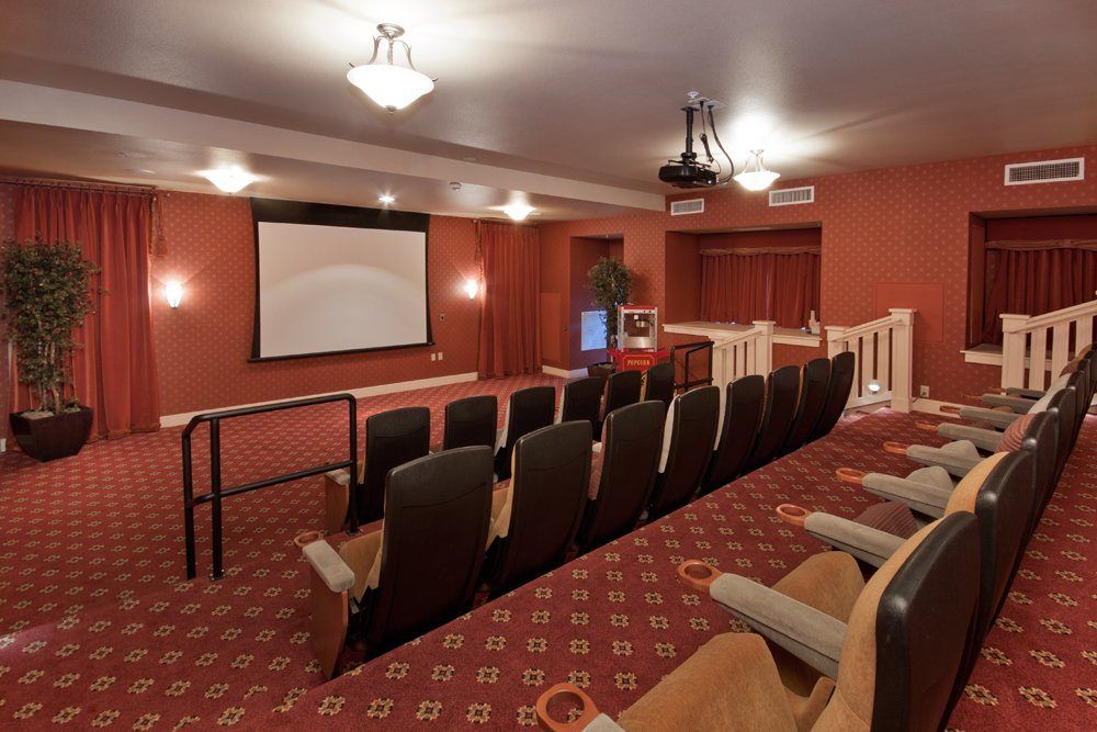 A cozy home theater with tiered seating, featuring a large projector screen and ambient lighting.