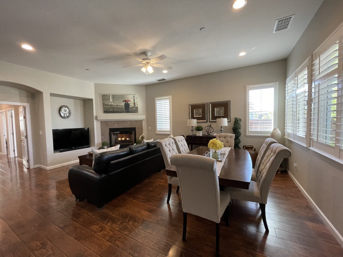 A modern open-concept living and dining area with a fireplace, featuring hardwood floors, comfortable seating, and natural lighting.