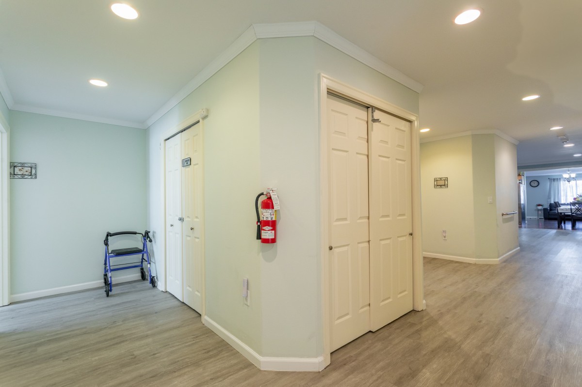 A well-lit hallway with multiple doors and a fire extinguisher mounted on the wall.