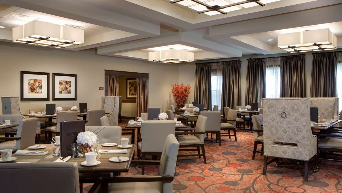 An elegant restaurant dining area with neatly arranged tables and chairs, featuring stylish lighting and decor.