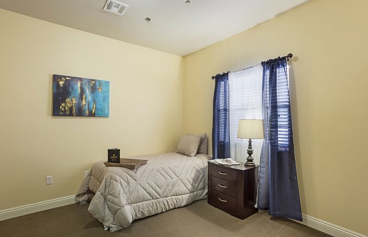 A cozy bedroom with a single bed, nightstand, and soft lighting.