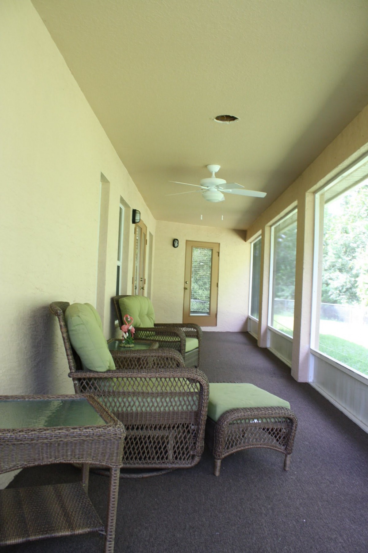 A cozy porch with comfortable chairs and large windows providing a view of the outdoors.