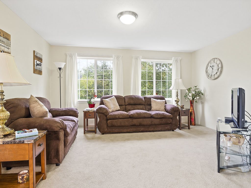 A cozy living room with sofas, a coffee table, and large windows.