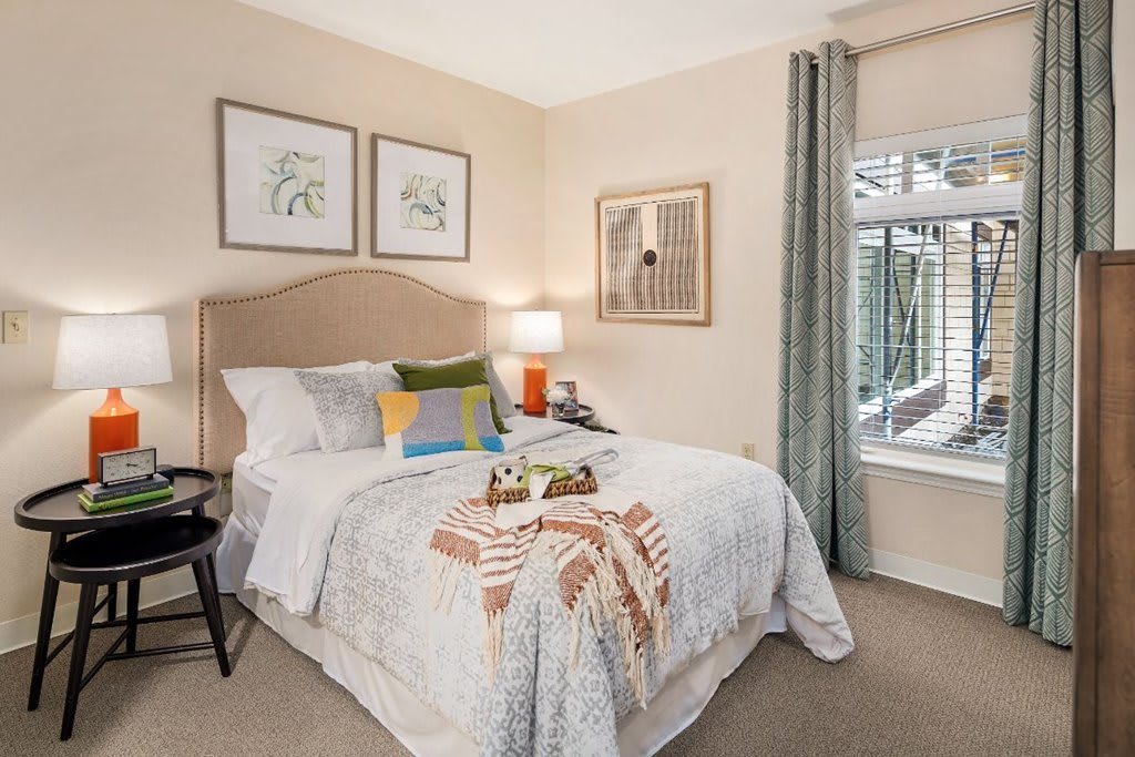 A cozy and well-decorated bedroom with a neatly made bed, colorful pillows, and framed artwork on the walls.