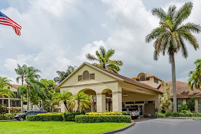 A tropical resort entrance surrounded by palm trees and lush landscaping.