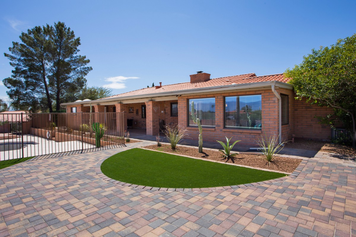 Modern brick house with a landscaped yard and paved driveway.