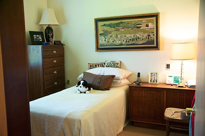 A cozy bedroom with a single bed, adorned with a plush toy, and decorated with a large painting above the headboard.