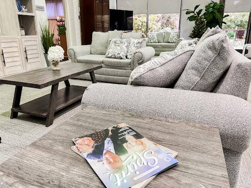 A cozy living room setup featuring a stylish sofa and a coffee table adorned with a magazine.