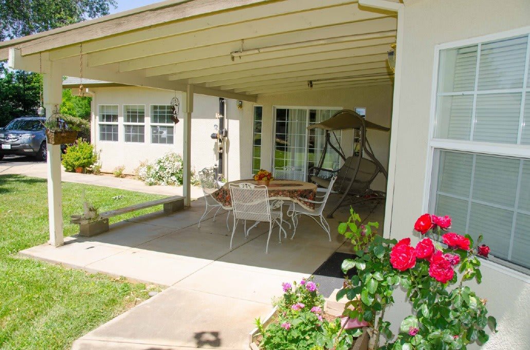 A cozy backyard patio with seating area and blooming roses.