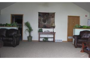 A cozy living room with a table, wall art, and potted plants.