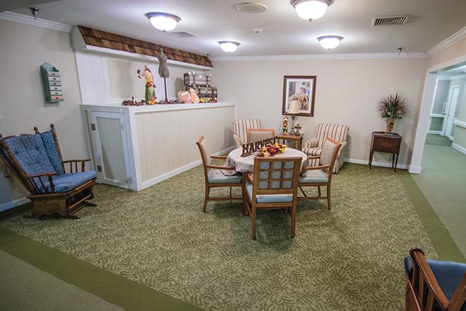 A cozy living area with a round table surrounded by chairs, decorative items, and soft lighting.