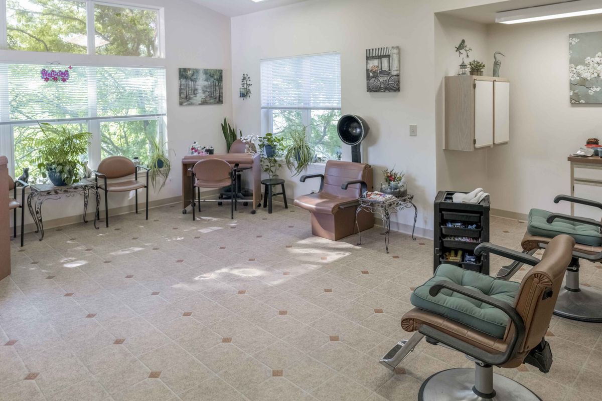 A spacious hair salon with comfortable seating, styling stations, and natural lighting.