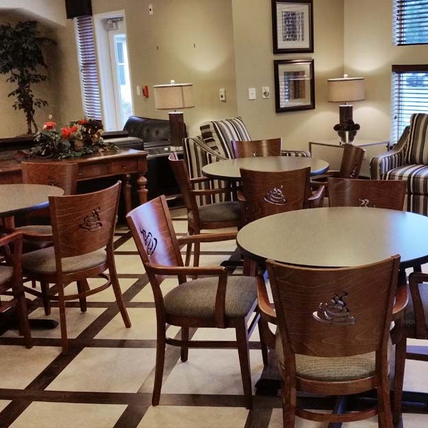 A cozy lobby seating area with tables and chairs, elegantly furnished and well-lit.