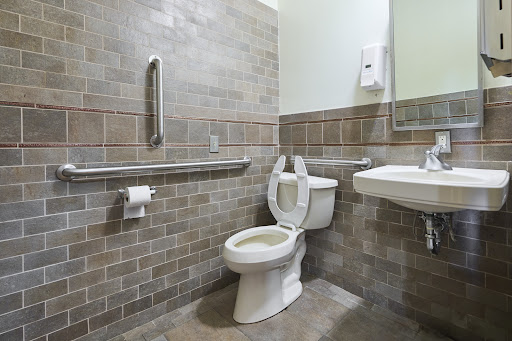 A clean and accessible bathroom featuring a toilet, sink, and grab bars.