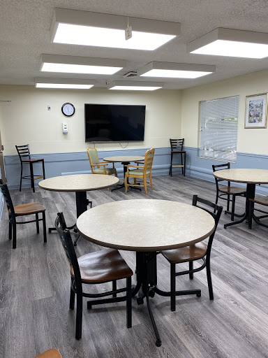 A well-lit indoor room featuring several round tables and chairs, suitable for meetings or gatherings.