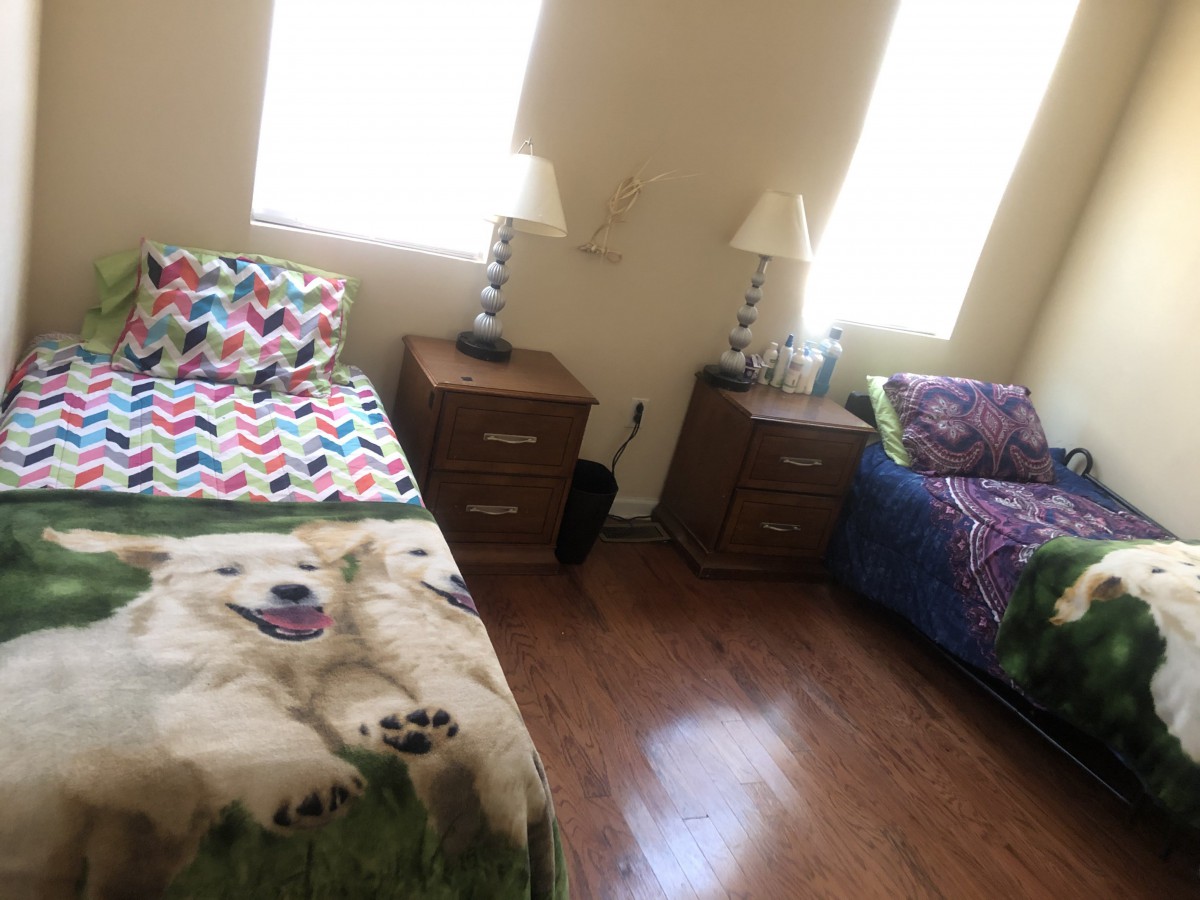 A cozy bedroom with two twin beds, each adorned with colorful blankets, and two bedside tables with lamps on a wooden floor.