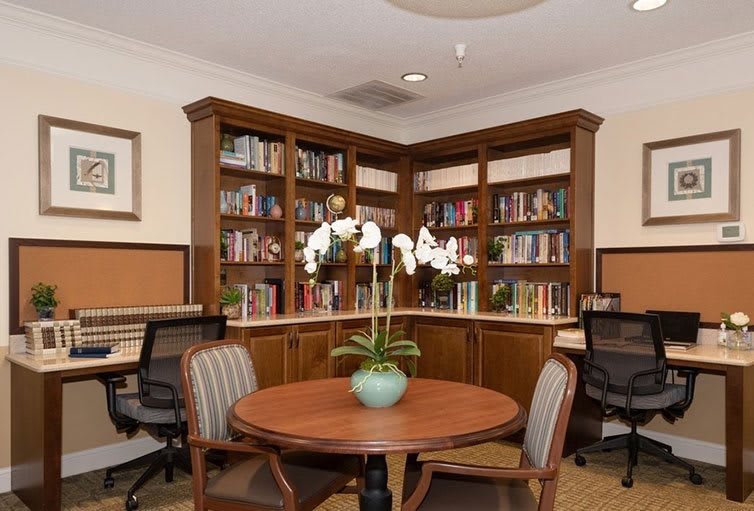 A cozy library corner with bookshelves, a round table, and chairs.