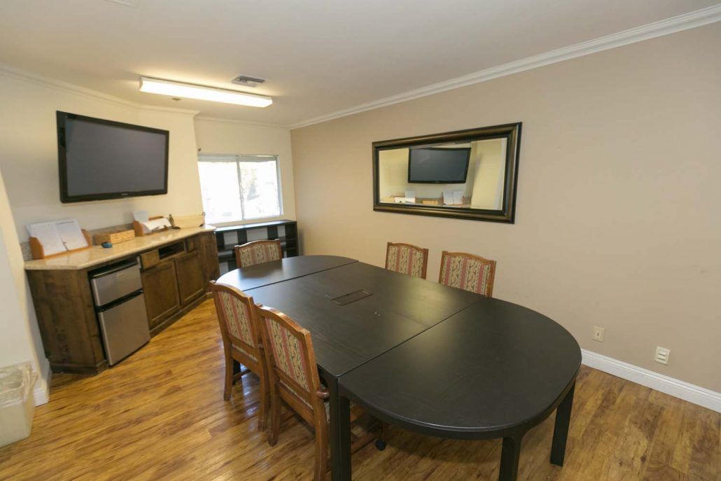 A well-organized conference room with a large meeting table, chairs, and a wall-mounted flat screen TV.