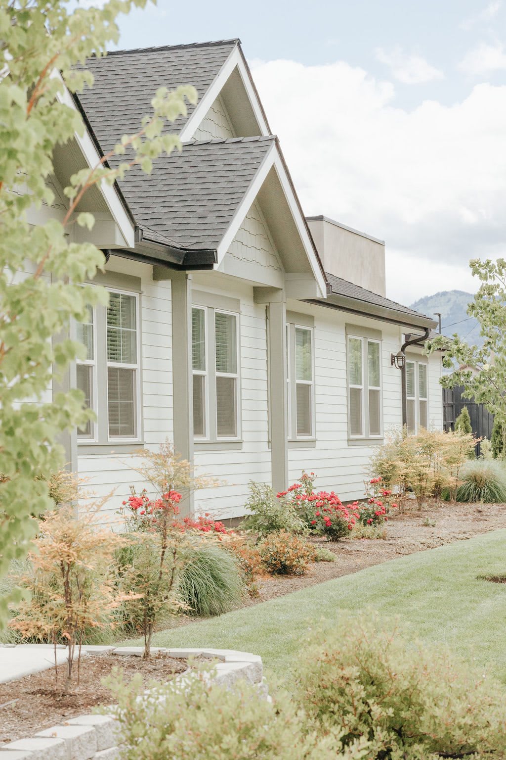 A charming white house with well-maintained landscaping and lush greenery.