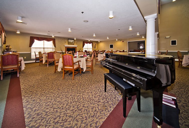 A spacious dining area with elegantly arranged tables and a grand piano.