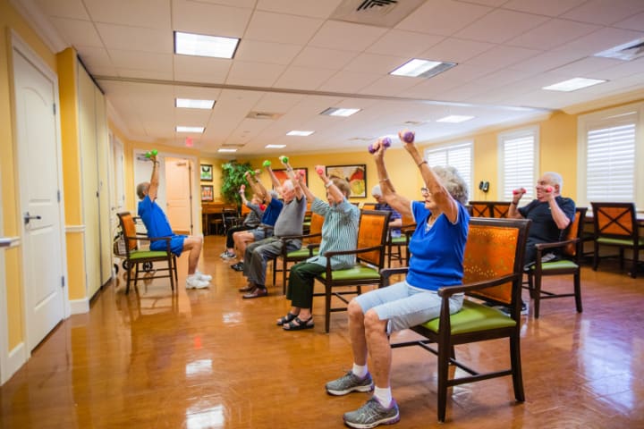 A group of seniors participating in a chair exercise class indoors.