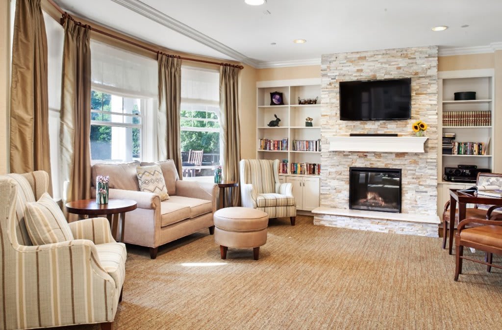 A cozy and modern living room with a fireplace, sleek furniture, and large windows.