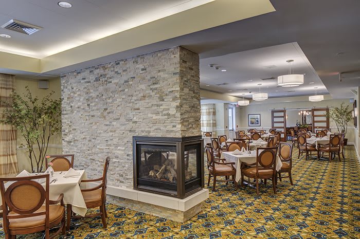 Cozy dining room featuring a central fireplace and elegantly arranged tables and chairs.