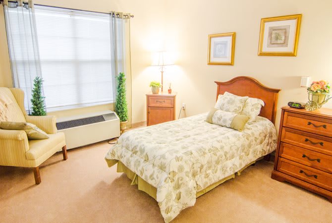 A cozy bedroom with a single bed, lamp, and window.