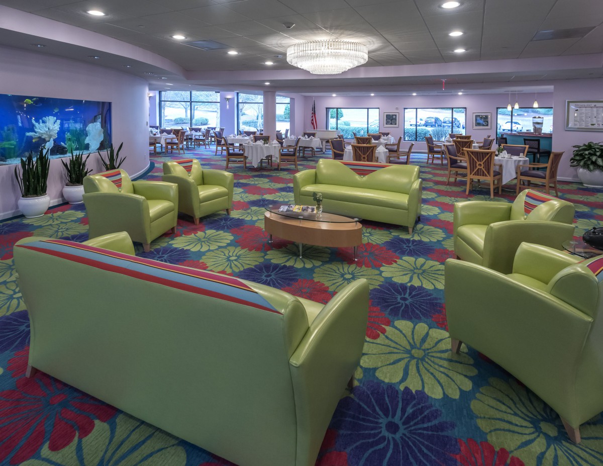 A modern lounge area with green couches and a vibrant, colorful carpet.