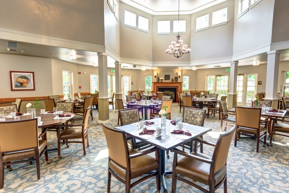 An elegant dining room with neatly arranged tables and chairs under a chandelier.