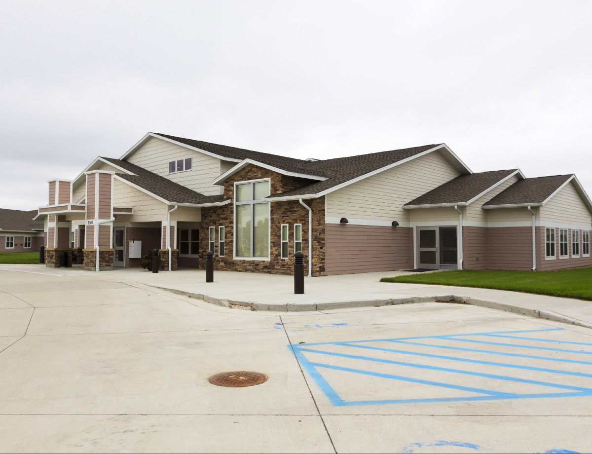 A modern building with a parking lot on a cloudy day.