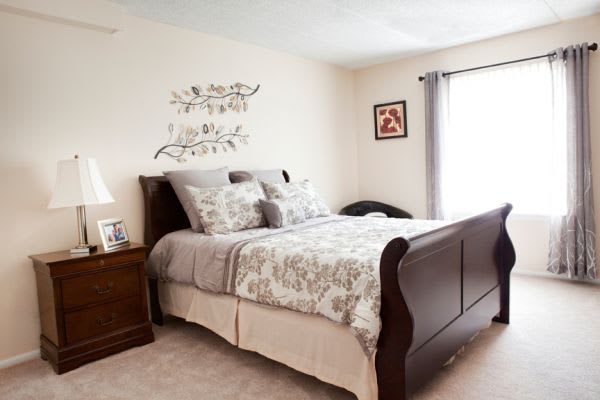 A cozy bedroom with elegant furniture and tasteful decor featuring a large wooden bed, neatly arranged bedding, and decorative wall art.