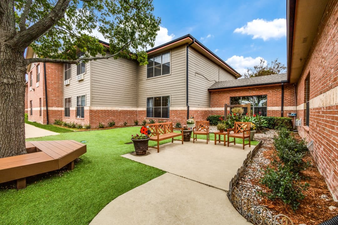 A well-maintained building with a landscaped garden featuring a pathway, benches, and lush green lawn.