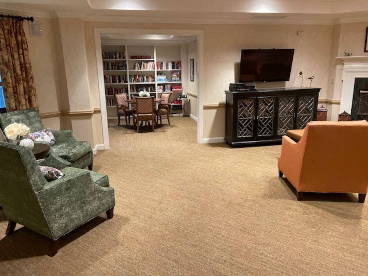 A cozy lounge area featuring comfortable seating, a television, and bookshelves stocked with books.
