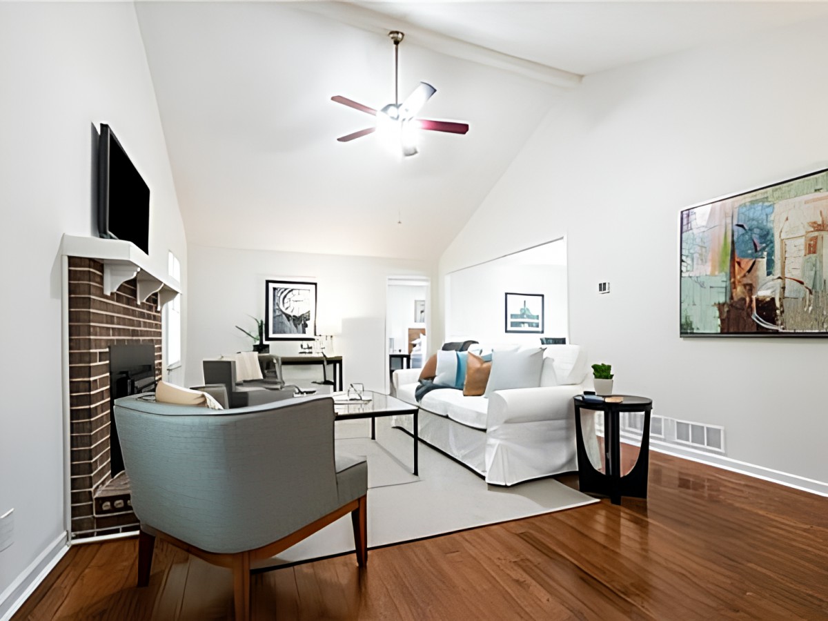 A modern living room with sleek furniture, wood flooring, and a ceiling fan.