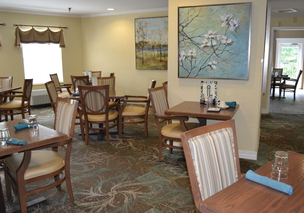 A cozy dining room with wooden chairs and tables, decorated with artwork on the walls.