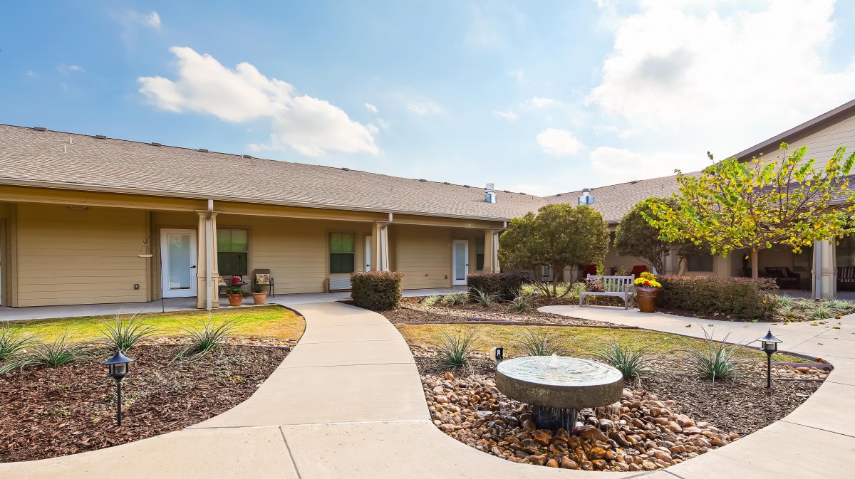 A well-maintained courtyard with a walking path and garden area in front of a building.