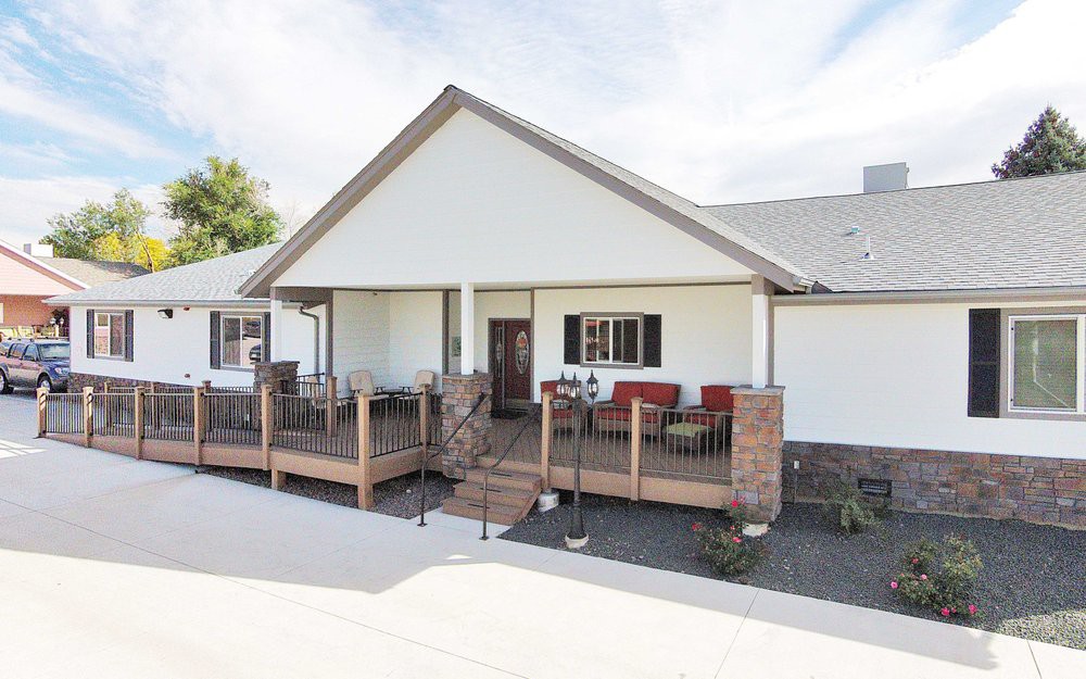 A residential house with a welcoming porch and deck, featuring outdoor seating and brick accents.
