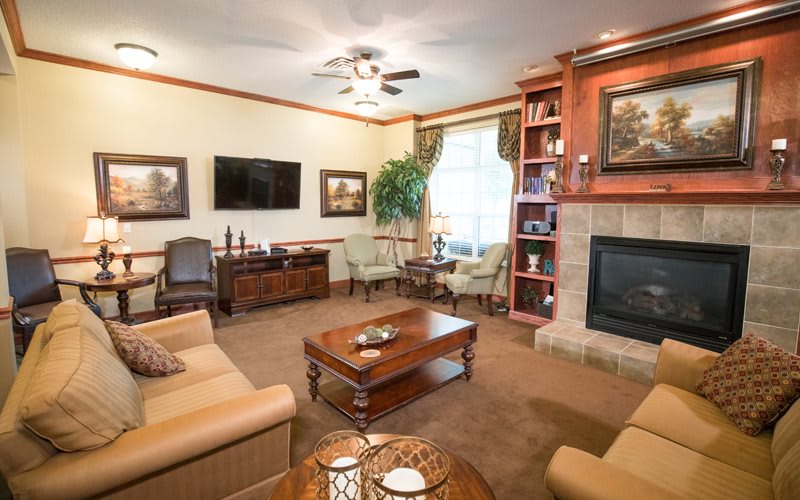 A cozy living room with warm lighting, featuring a comfortable seating area, a fireplace, and elegant decorations.