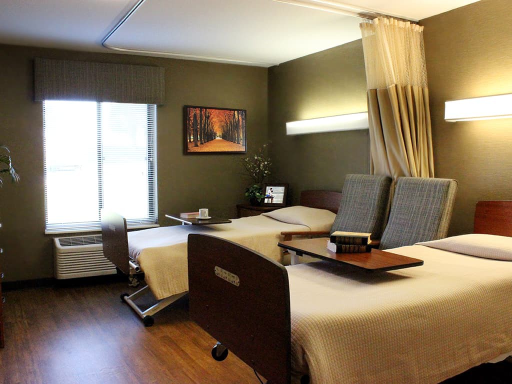 A modern hospital room with two patient beds and medical equipment.