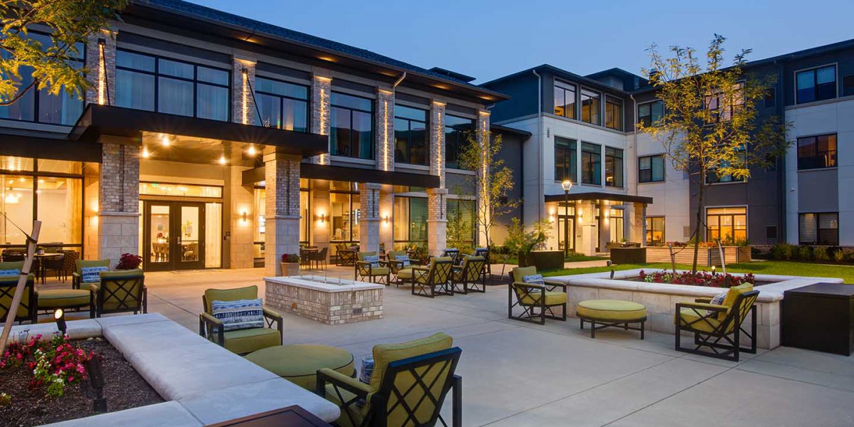A modern luxury building with outdoor seating and evening lighting.