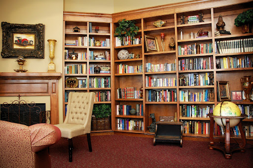 A warm and inviting corner of a library featuring wooden bookshelves filled with a variety of books, accompanied by comfortable seating.