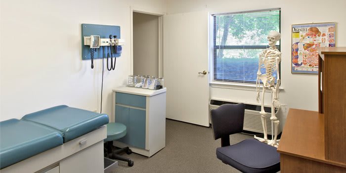 An examination room in a doctor's office, equipped with medical tools and seating.